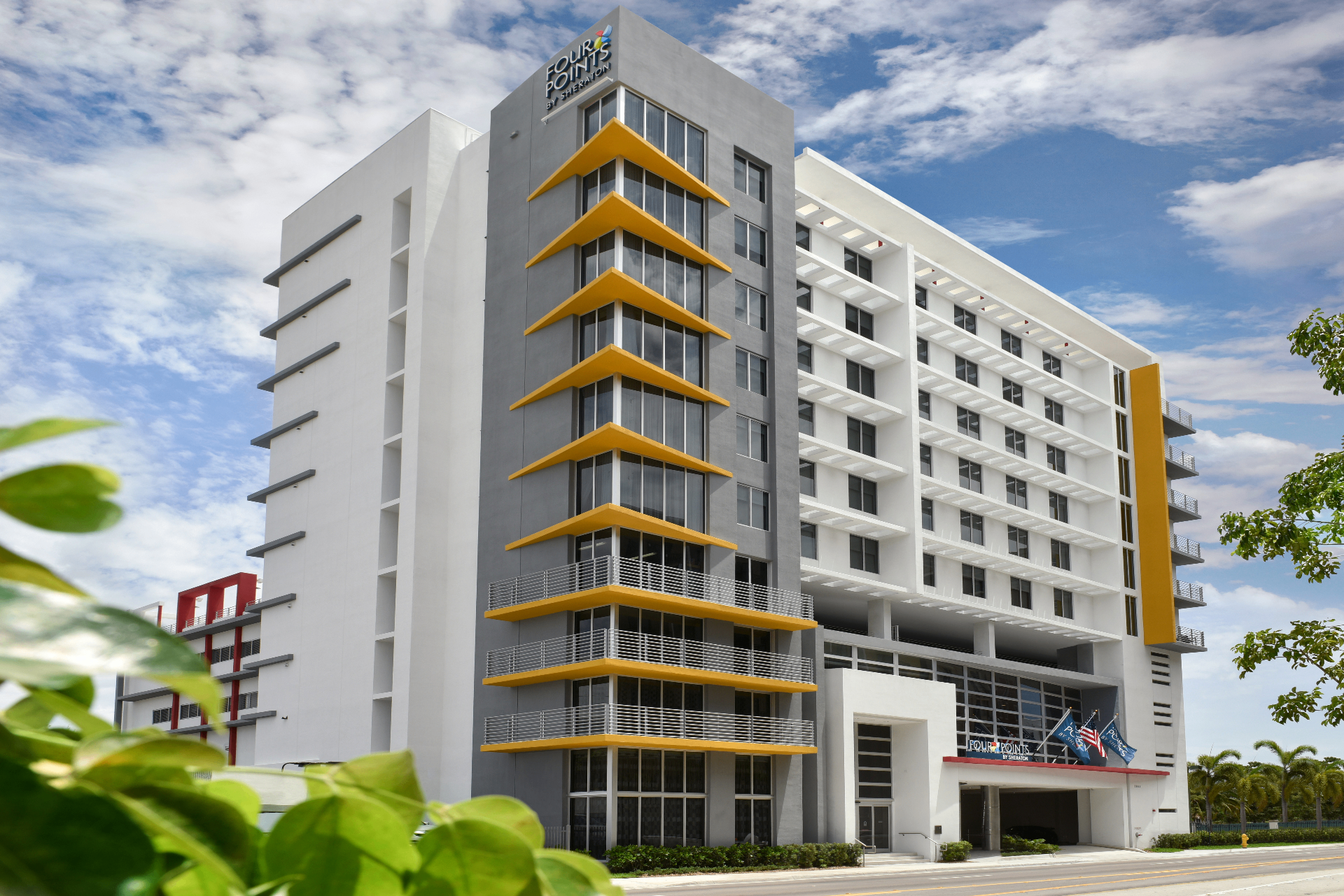 Contemporary mid-rise hotel tower with glass curtain wall and urban streetscape.