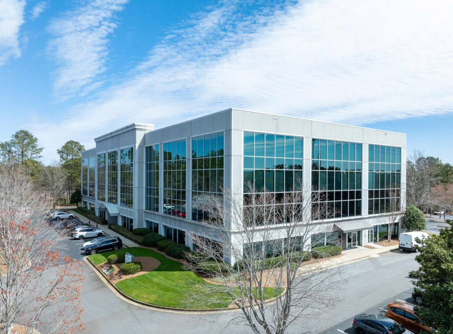 Exterior of a low-rise mixed-use building with balconies and ground-floor retail frontage.
