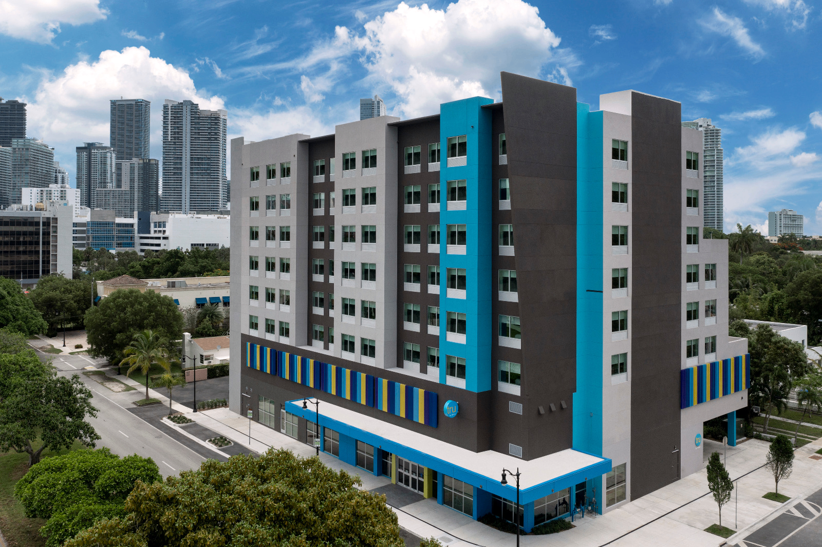 Modern select-service hotel facade with branded signage and porte-cochère entry.